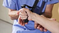 Patient grasps handle of exercise machine.